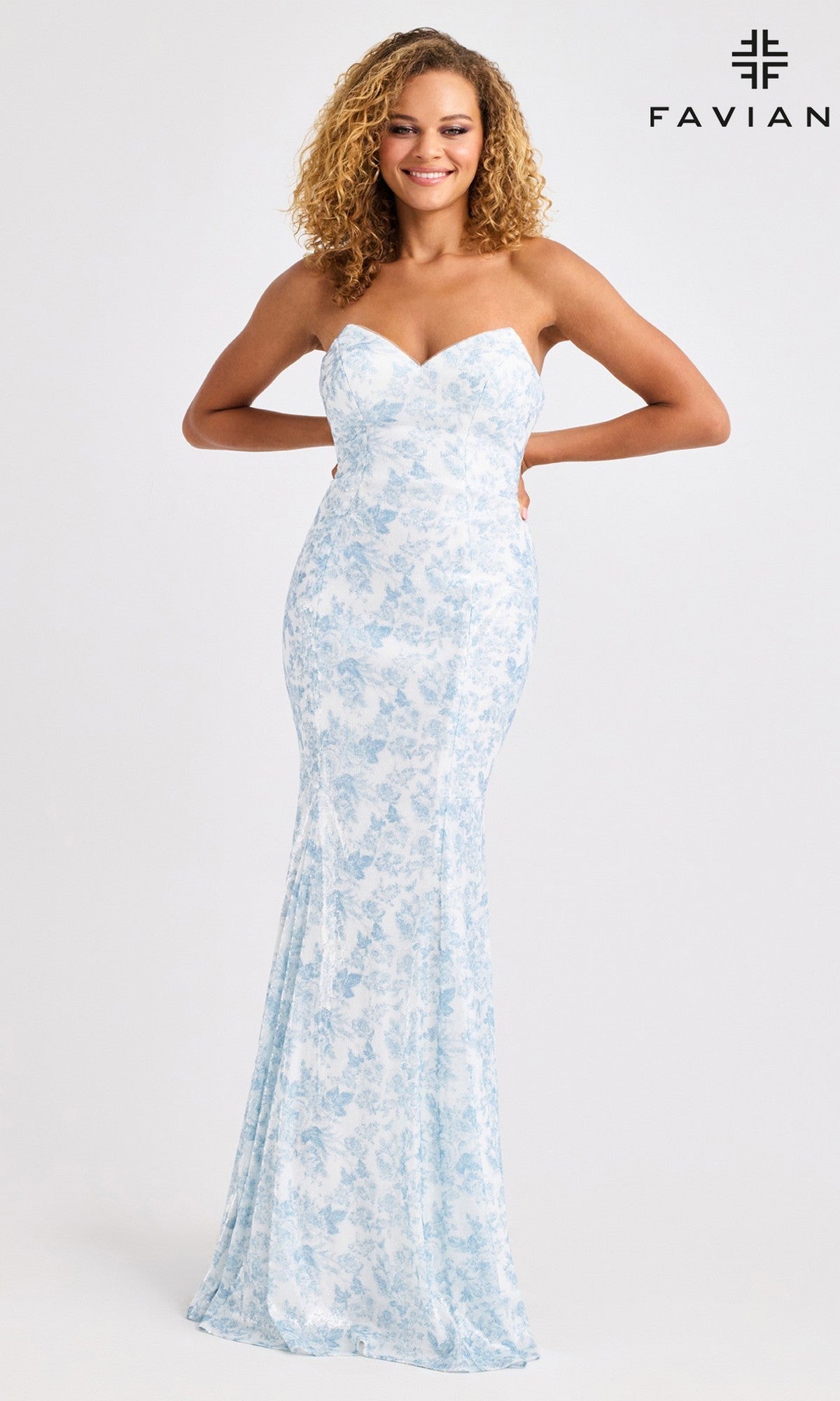 Model in Faviana 11441: a strapless, floor-length mermaid prom dress in white with a light blue floral pattern, posing before a plain background. Faviana logo appears in upper right corner.
