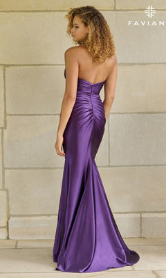 A woman with curly hair models the Faviana 11453 long prom dress—an elegant, floor-length purple satin gown with ruched back detailing—while standing against a stone wall.