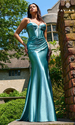 Wearing the Faviana 11454 long prom dress in metallic teal satin with a corset bodice, a woman stands outdoors by a historic building and brick pillar under a clear sky.