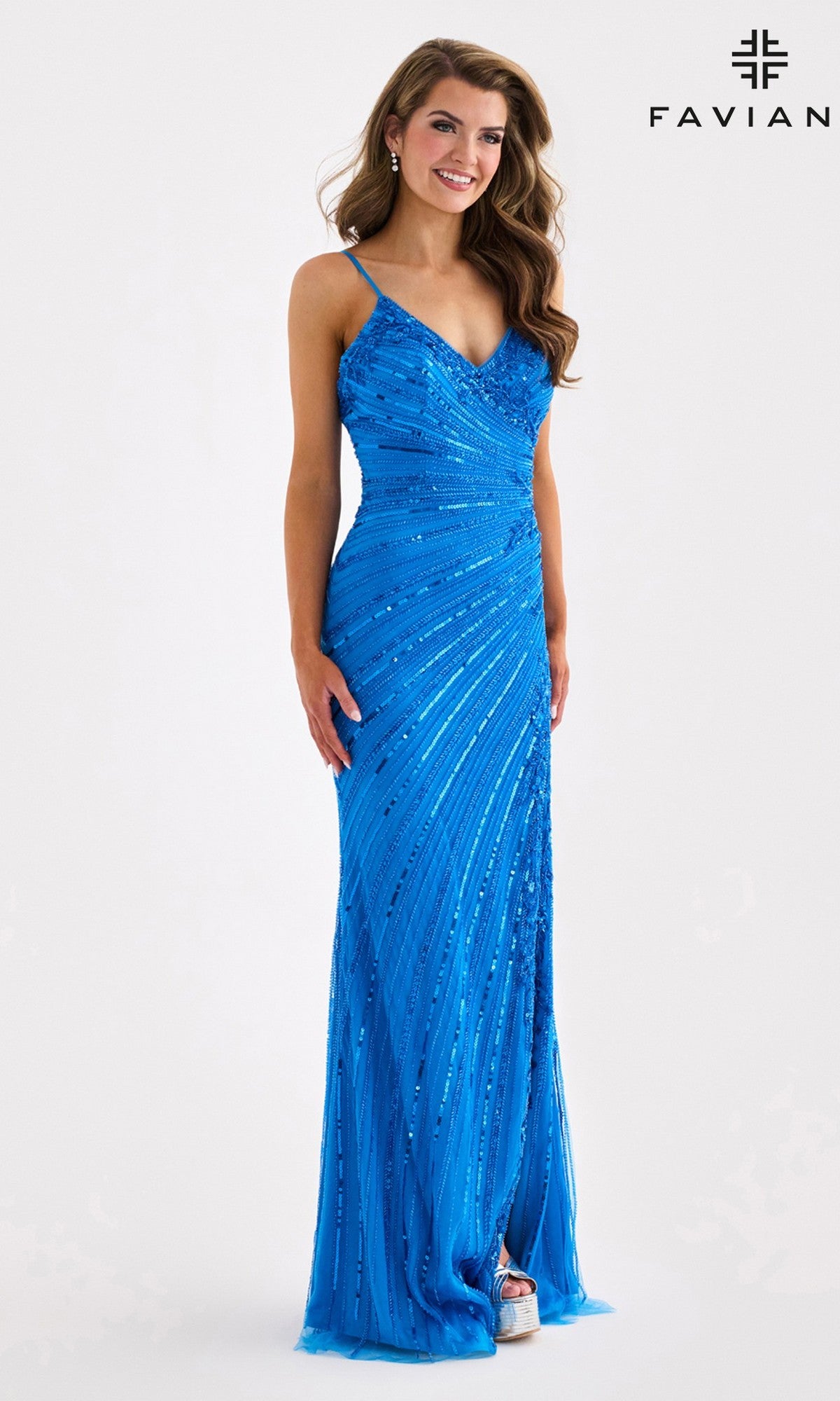 A woman in the Faviana 11462 long prom dress—bright blue, floor-length with sequins, v-neckline, and thin straps—stands smiling against a white background. The 