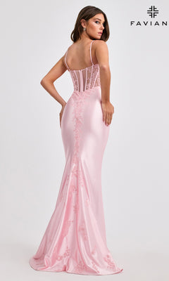 A woman in a pale pink, floor-length Faviana 11466 prom dress with beaded embroidery, delicate lace details, and a semi-sheer fitted bodice stands facing away. The "FAVIANA" logo is visible in the upper right corner.