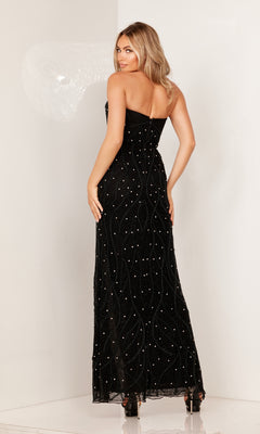 A woman poses with her back turned in the Deep V-Neck Strapless Long Beaded Prom Dress 1148, a floor-length black gown with sparkling embellishments and wavy patterns, set against a plain light background.