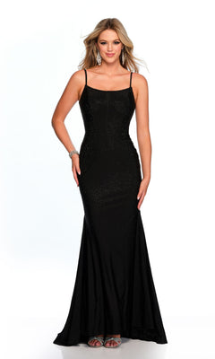 A woman wears the Long Formal Dress 11576 by Dave and Johnny—a fitted black gown with a scoop neckline and thin straps—paired with silver earrings, a bracelet, and sandals, standing against a plain white background.