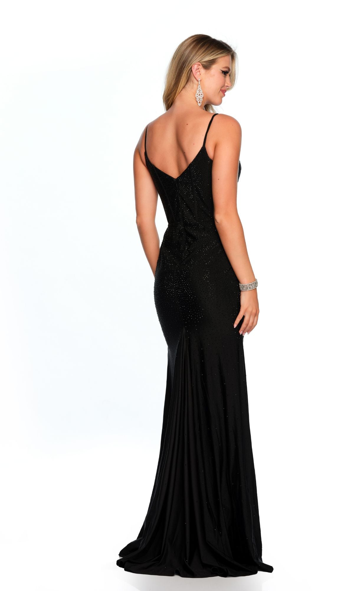 A woman in the Long Formal Dress 11576 by Dave and Johnny, a fitted black gown with thin straps, stands facing away from the camera against a white background.