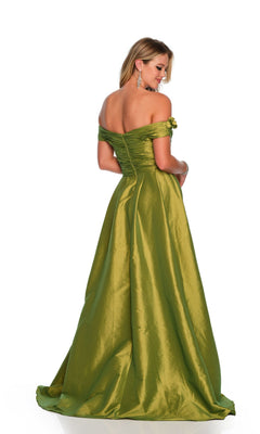 A woman stands facing away, wearing the Long Formal Dress 11581 by Dave and Johnny—an off-the-shoulder, floor-length olive green gown featuring a shiny finish and ruched bodice, complemented by her long hair and statement earrings.