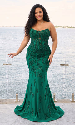 A plus-size woman wears the Faviana 11600E, a dark emerald, strapless corset gown with a floor-length silhouette and beaded floral embroidery.