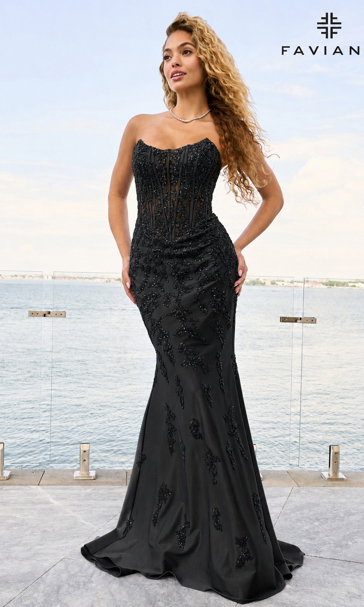 A woman wears a black, floor-length, strapless Faviana 11600 prom dress with a corset-style bodice and intricate beaded embroidery throughout.