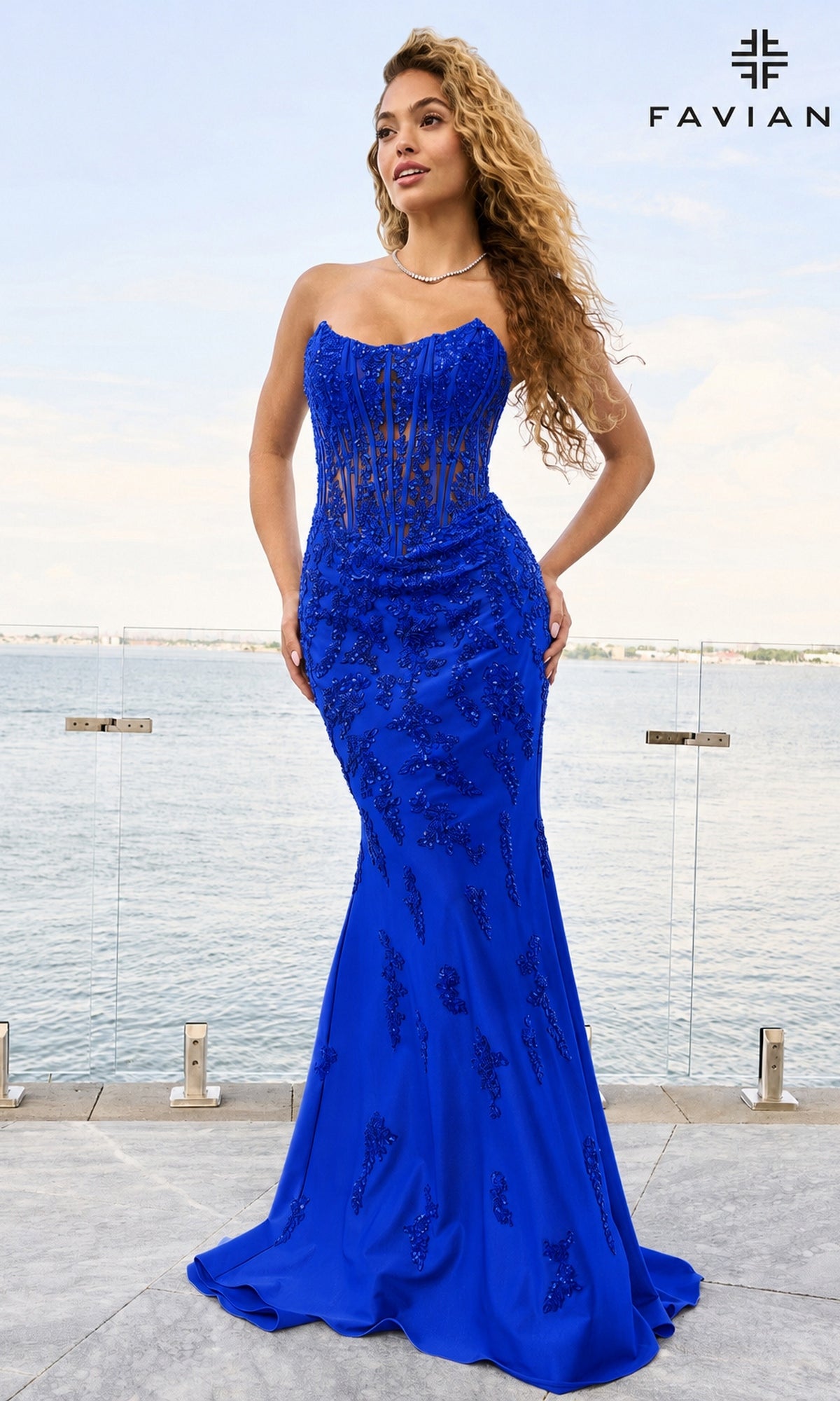 A model wears a royal blue, floor-length Long Prom Dress: Faviana 11600 featuring a strapless, corset-style bodice with floral embroidery.