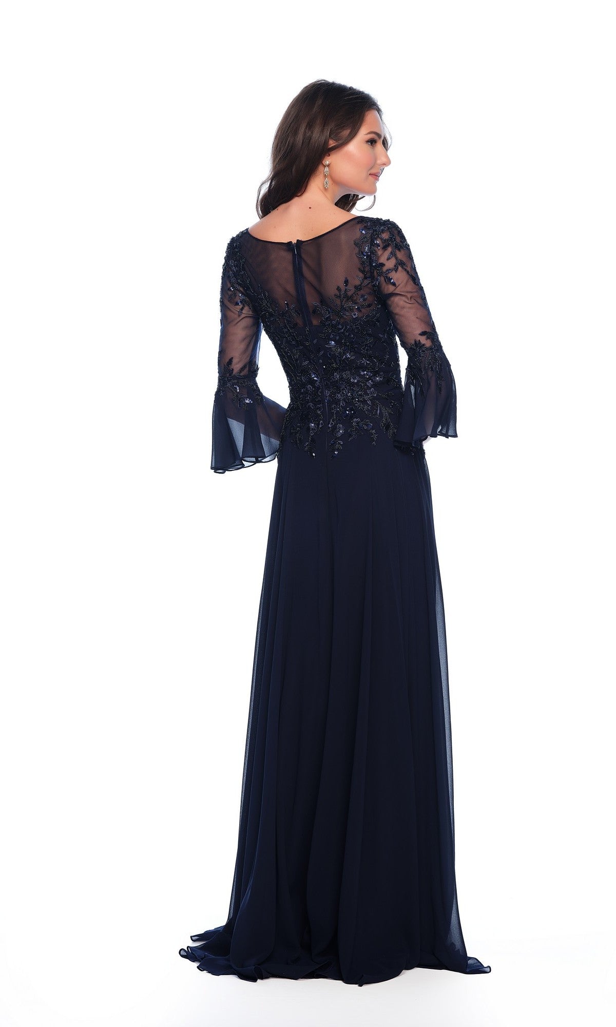 A woman wears the Long Formal Dress 11602 by Dave and Johnny, a navy blue, floor-length gown featuring a v-neckline with sheer, embroidered sleeves and back, posing against a plain white background.