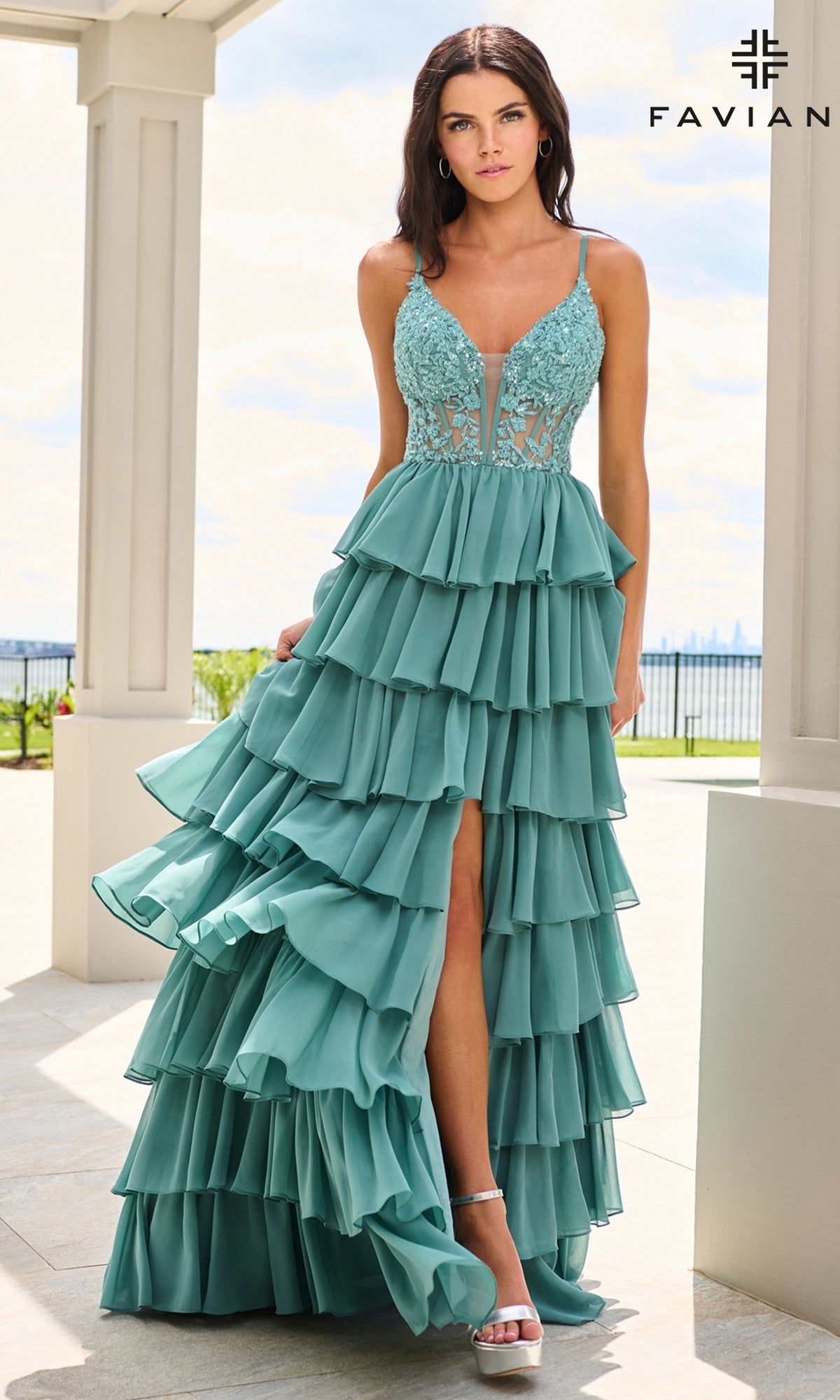 A model wears the Long Prom Dress: Faviana 11603, a dark Pacific blue floor-length A-line gown featuring a beaded corset bodice, tiered ruffles, and a high slit.