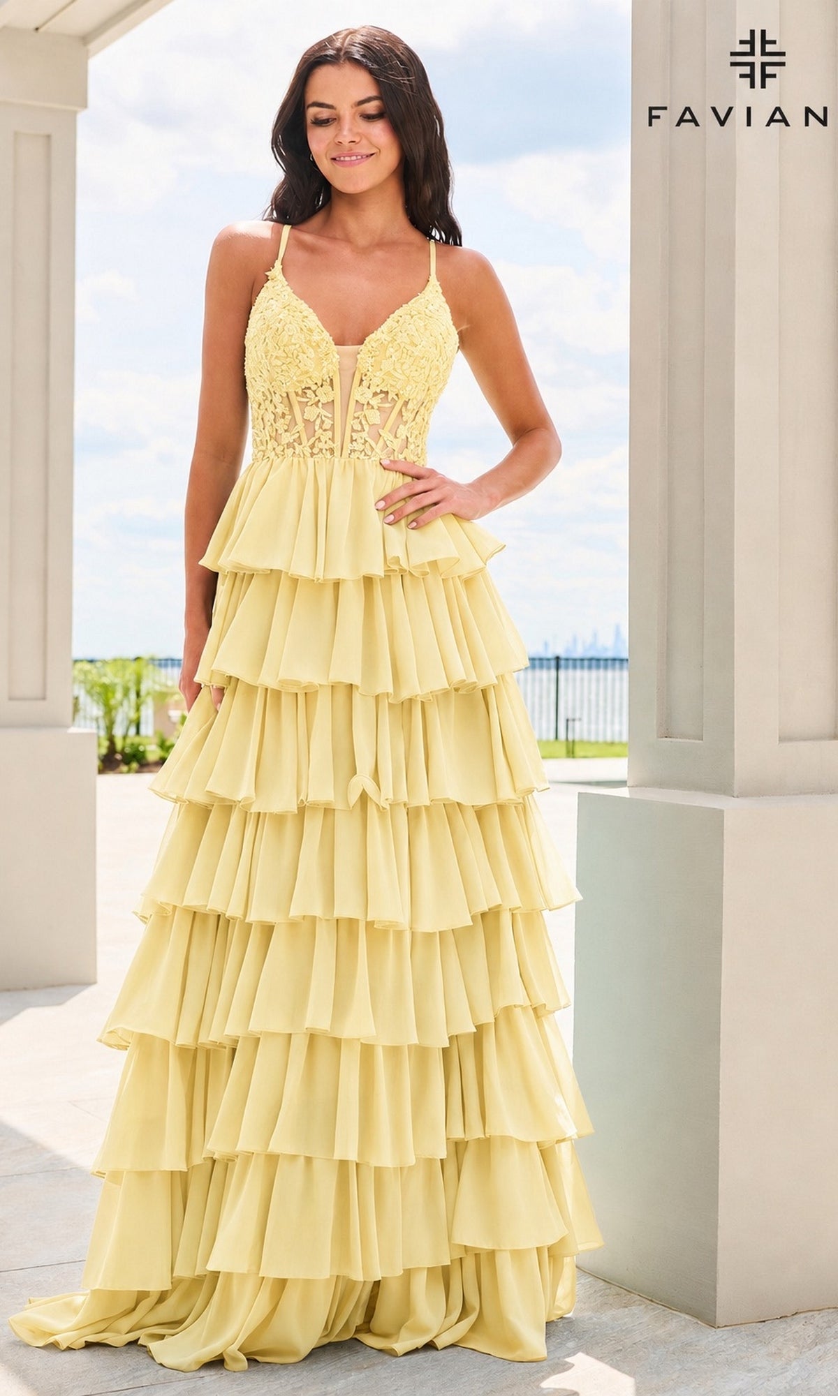 A woman wears a light yellow, A-line Faviana 11603 prom dress featuring a corset bodice and a tiered, ruffled chiffon skirt.