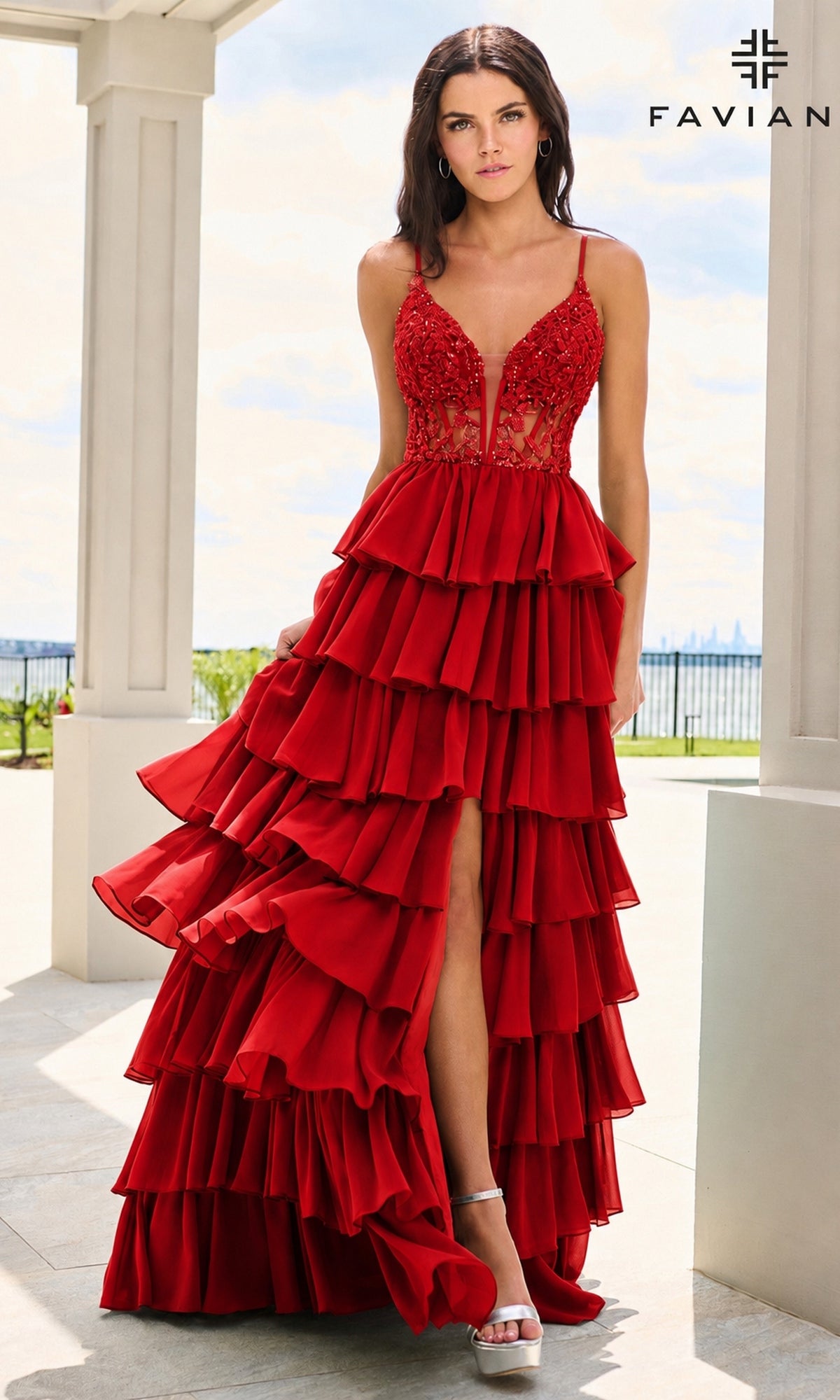 A woman wearing a red, floor-length Faviana 11603 A-line prom dress with a corset bodice, beaded detailing, and a high leg slit.