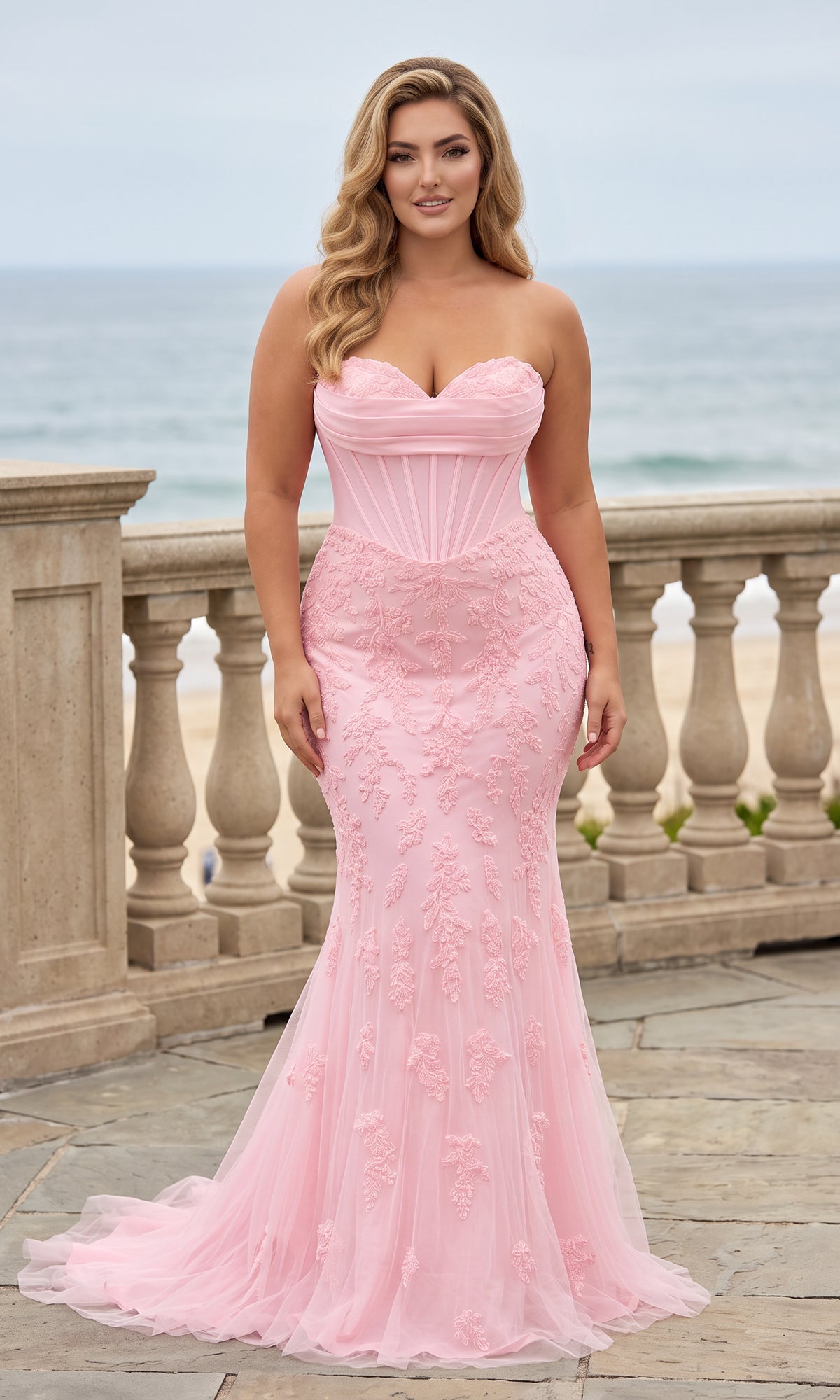 A woman wearing a light pink, strapless, floor-length Long Plus-Size Prom Dress: Faviana 11604E featuring a corset-style bodice with floral embroidery.