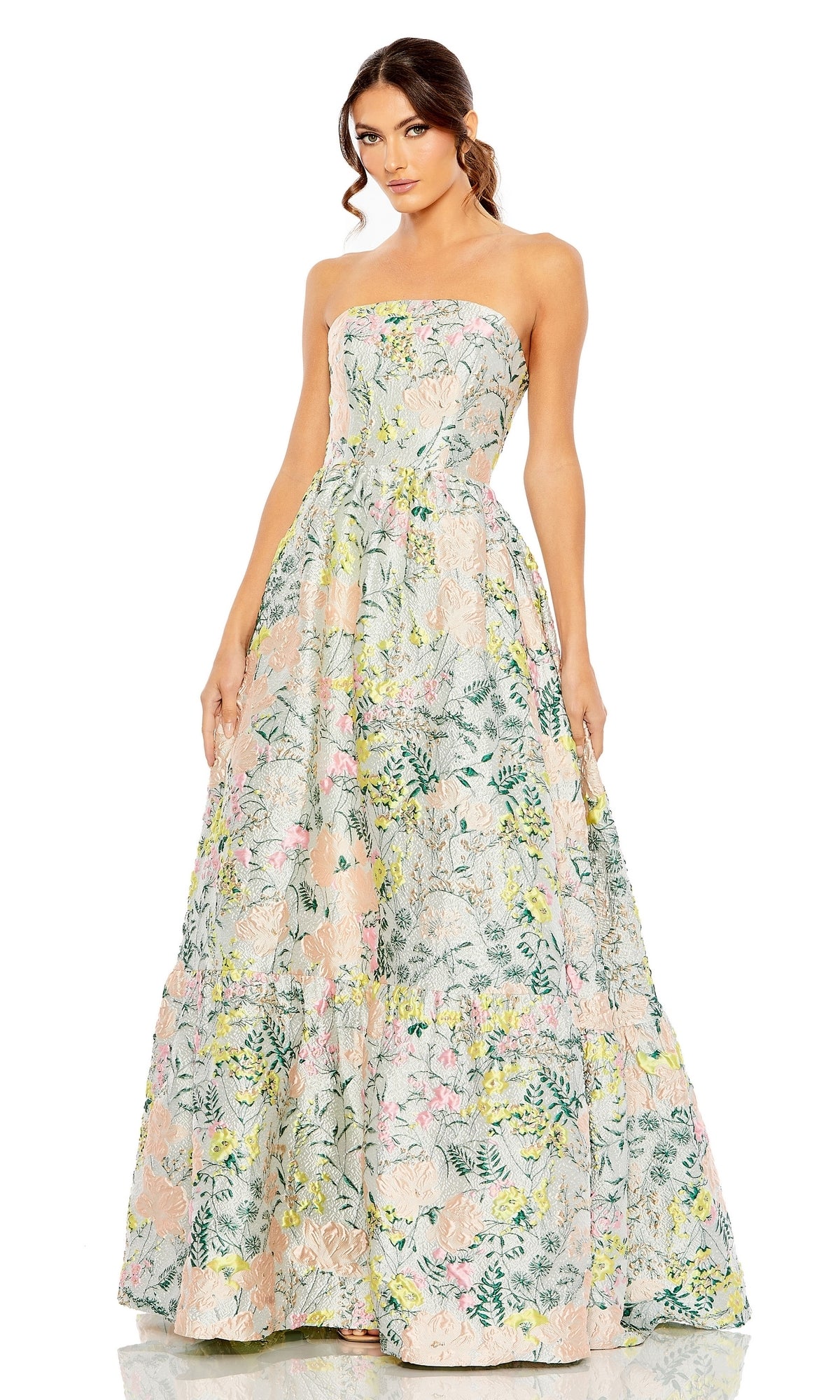 A woman wears the Strapless Brocade Formal Gown: Mac Duggal 11604, a floor-length, strapless dress with a full skirt and nature-inspired pastel floral print.