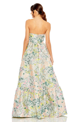 A woman faces away from the camera in a Mac Duggal 11604 Strapless Brocade Formal Gown, showcasing a pastel floral pattern, with her hair styled in a low ponytail.