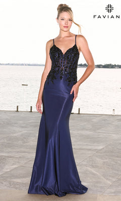 A woman models a navy blue Faviana 11608 floor-length gown with a sweetheart neckline and a black beaded corset bodice featuring a sheer panel.