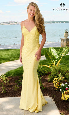 A woman wearing a floor-length, light yellow sleeveless V-neck Faviana 11611 prom dress embellished with pearls.