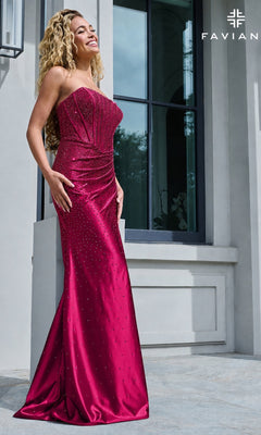 A woman wearing a cherry-colored Faviana 11613 long prom dress, a strapless, floor-length corset gown with scattered rhinestone embellishments.