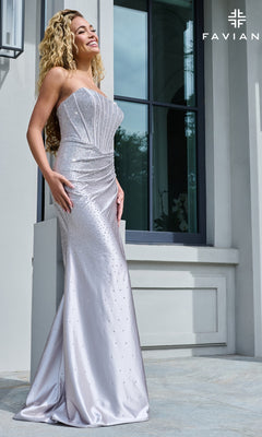 A woman wearing the Faviana 11613 long prom dress, a strapless, floor-length silver gown with a corset-style bodice and scattered rhinestone embellishments.