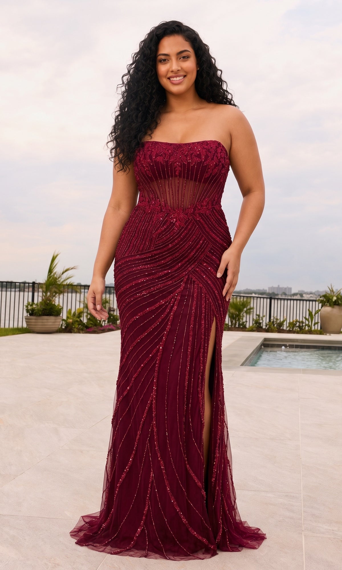 A plus-size woman in a cherry-red Long Plus-Size Prom Dress: Faviana 11615E, featuring a strapless, sheer, vertically beaded bodice and a high side slit.