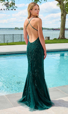 A woman stands by a pool wearing a Faviana 11626 long prom dress in dark hunter green, featuring a floor-length backless tulle design with intricate beaded lace appliques.
