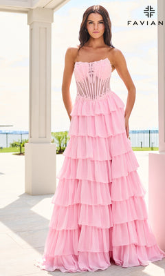 A woman wears a light pink, floor-length Faviana 11629 prom dress with a corset bodice and a tiered, ruffled skirt.