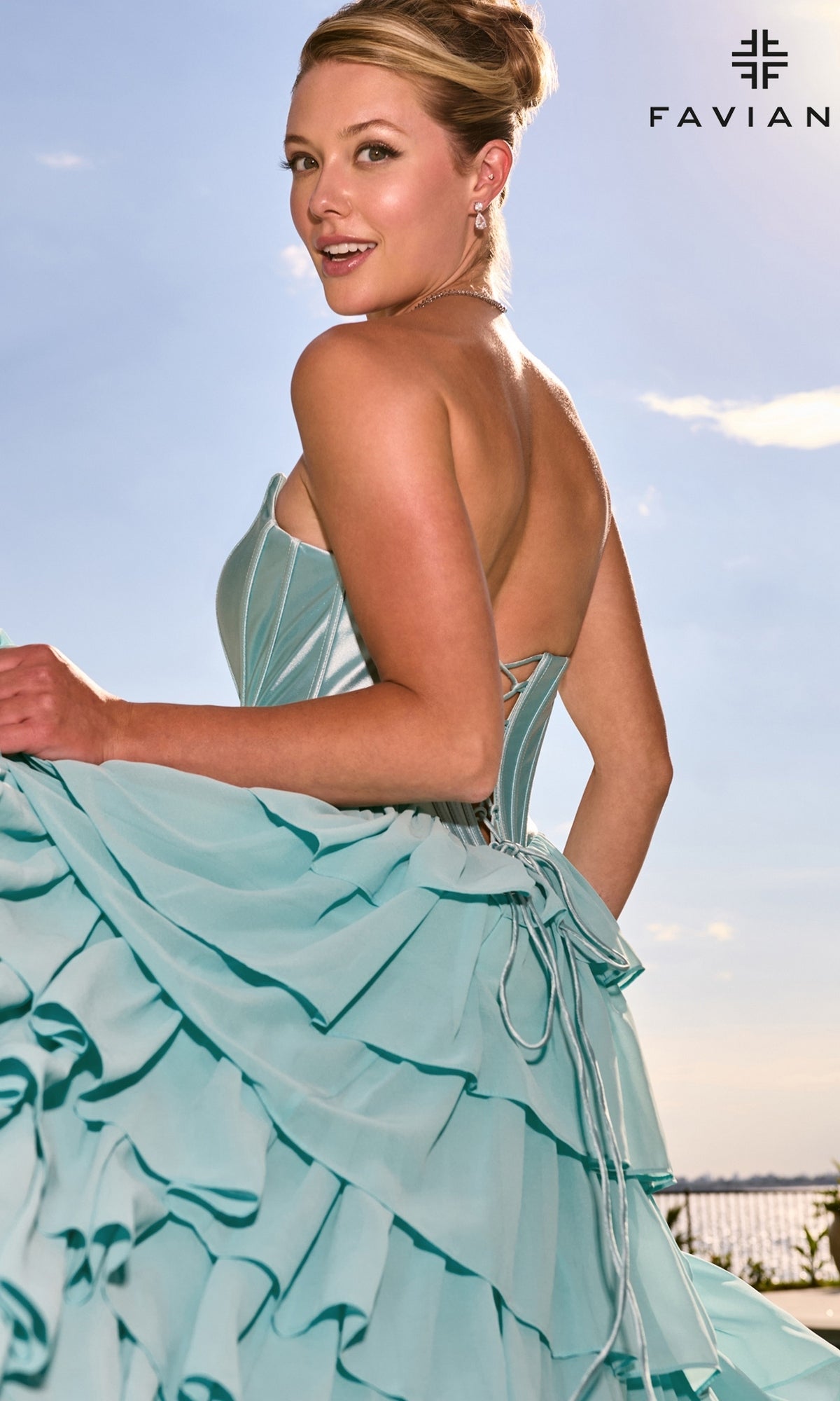 Woman wearing a light blue Faviana 11631 prom dress with a satin corset bodice, a strapless neckline, and a ruffled skirt.