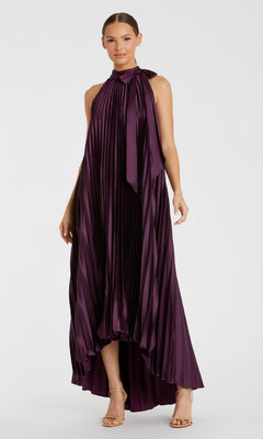 A woman wears the Mac Duggal 11639, a long plum purple formal dress with a sleeveless, pleated design, high-low hem, high neckline, and bow detail—ideal for special occasions.