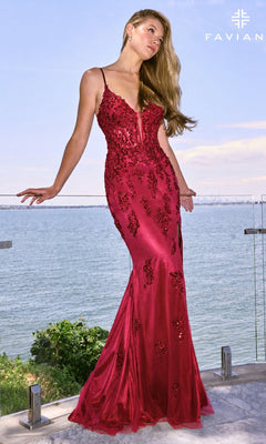 A woman stands on a balcony overlooking the water in a cherry-red Faviana 11641 long prom dress with a plunging neckline, sequin embellishments, and a side slit.