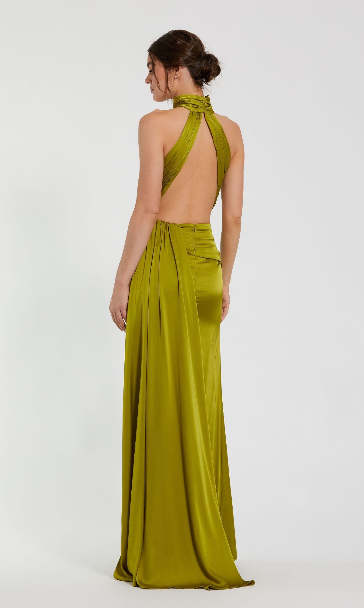 A woman wears the Mac Duggal 11642 High-Neck Long Prom Dress—an olive green, floor-length gown with a backless design, halter neckline, and gathered fabric details—standing against a plain white background.