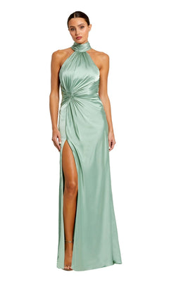 A woman wearing the Mac Duggal 11642—a high-neck, sleeveless light green satin prom dress with a gathered waist knot and thigh-high slit.