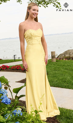 A woman wears a light yellow Faviana 11647 long prom dress, a strapless floor-length gown with floral beaded appliques on the bodice, while standing outdoors near a waterfront.