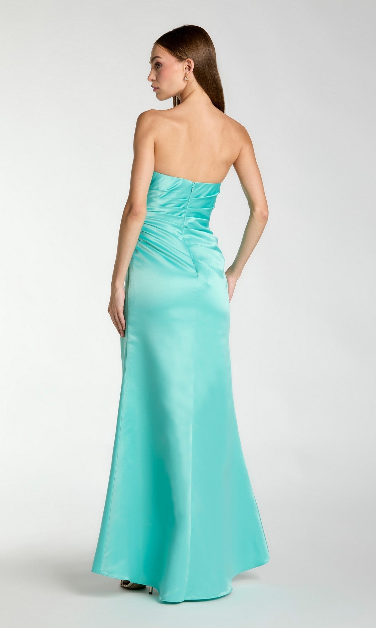A woman faces away, wearing the Sherbet Orange Long Prom Dress by Mac Duggal 11653—strapless, floor-length, with back ruching and luminous satin fabric.