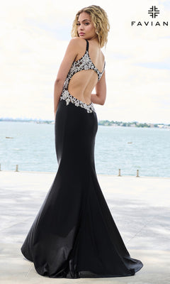 A woman wearing a black V-neck Long Prom Dress: Faviana 11655, featuring a floor-length skirt, an open back, and silver beaded appliques along the neckline and waistline.