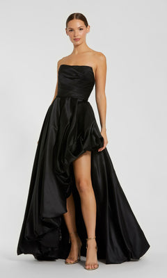 A woman stands against a plain light background, wearing the Mac Duggal 11685 Strapless Balloon Prom Dress with an asymmetrical hem and gold strappy heels.