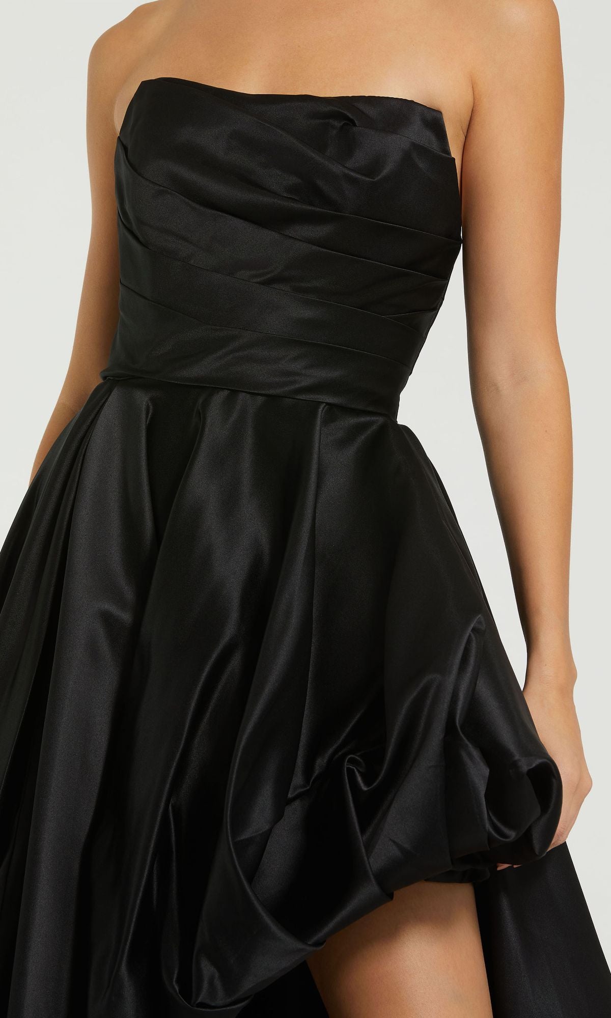 A person wearing the Mac Duggal 11685 Strapless Balloon Prom Dress, featuring a strapless black satin bodice and a voluminous, draped skirt for an elegant long formal look.