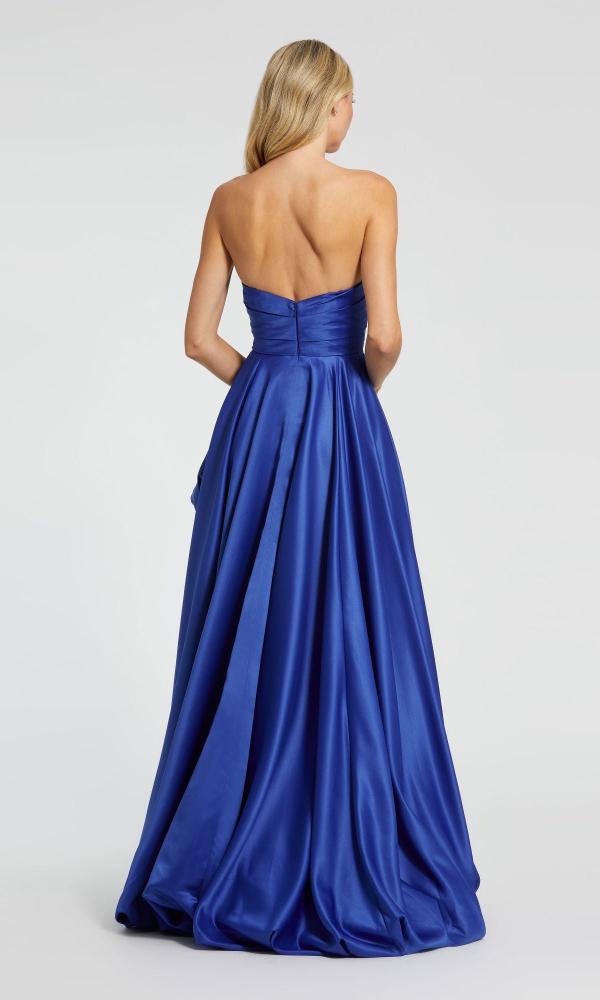 A woman faces away, wearing the Strapless Balloon Prom Dress: Mac Duggal 11685—a strapless, floor-length royal blue satin gown featuring a fitted bodice and full skirt.