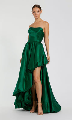 A woman wears the Strapless Balloon Prom Dress: Mac Duggal 11685, an emerald green strapless high-low gown with a ruched bodice and flowing skirt, paired with strappy heels.