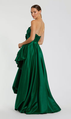 A woman models the Mac Duggal 11685 Strapless Balloon Prom Dress in floor-length emerald green, featuring a draped skirt, as she stands facing backward and glances over her shoulder.