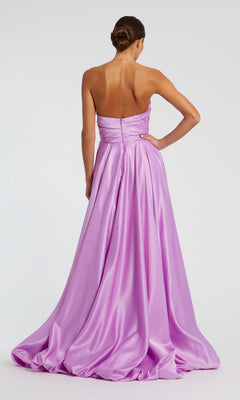 A woman faces away from the camera in a lavender satin Strapless Balloon Prom Dress by Mac Duggal 11685, featuring a floor-length full skirt, with her hair in a low bun.