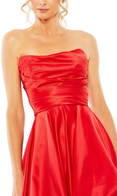 A woman wears the Strapless Balloon Prom Dress: Mac Duggal 11685—a shiny red gown with a fitted bodice and flowing skirt. The image is cropped at the shoulders and knees.
