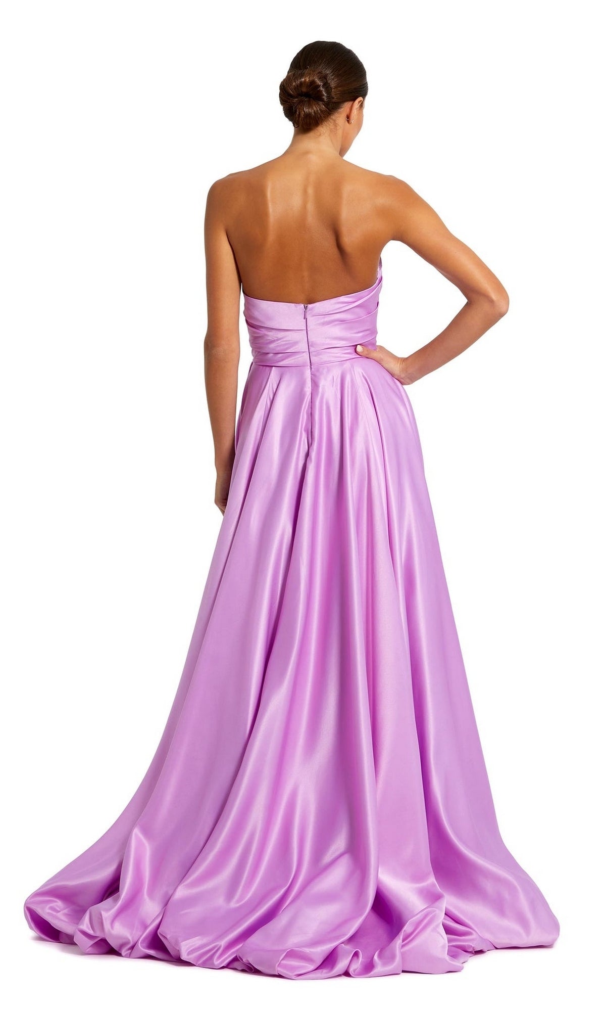 A woman stands with her back to the camera, wearing the Mac Duggal 11685 Strapless Balloon Prom Dress in lilac satin with a full skirt, her hair styled in a sleek bun.