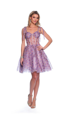 A woman stands against a white background wearing the Dave and Johnny Short Print Hoco Dress 11752—a purple floral party dress with a corset-style bodice, sheer accents, and bow-tied shoulder straps.
