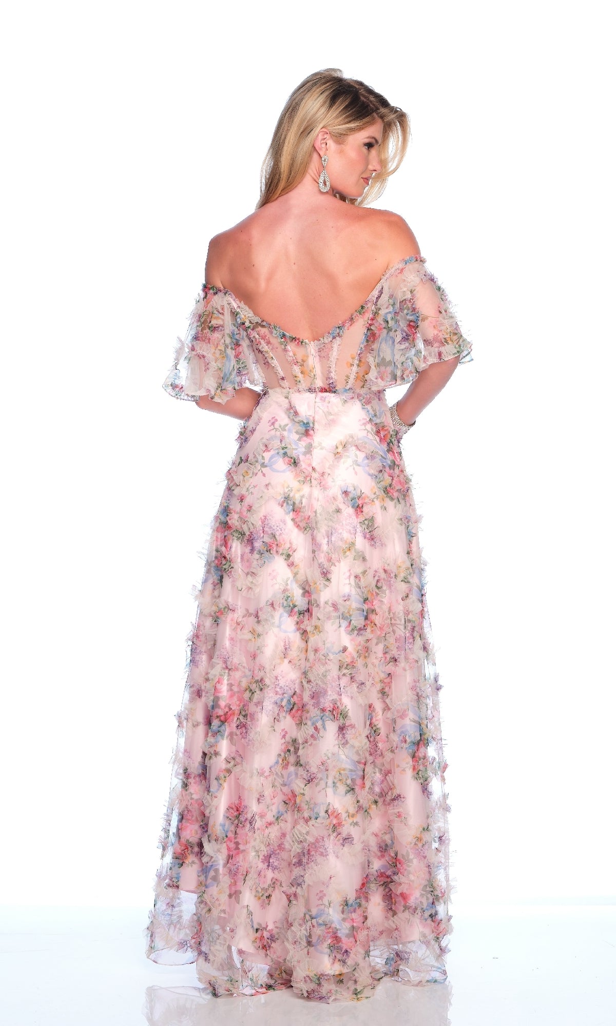 A woman faces away in the Dave & Johnny 11784 Pink Floral Prom Dress, featuring an off-the-shoulder design, sheer ruffled sleeves, and a floor-length elegant silhouette against a white background.