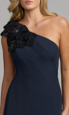 A woman wearing the Mac Duggal 11810 Beaded-One-Shoulder Prom Gown in navy, which features a striking one-shoulder design adorned with a large, beaded floral embellishment on the shoulder.