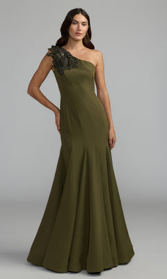 A woman is wearing the Beaded-One-Shoulder Prom Gown: Mac Duggal 11810 in Olive, which features black beaded embellishment on the single shoulder, as she stands against a plain grey background.