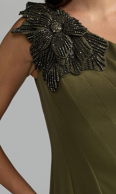 Close-up of a woman wearing the Beaded-One-Shoulder Prom Gown (Mac Duggal 11810), an olive green formal evening dress featuring a large, beaded floral embellishment on one shoulder.