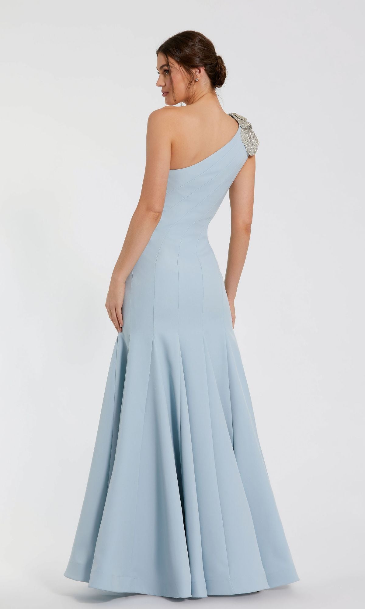 Woman in a light blue Mac Duggal 11810 beaded one-shoulder prom gown with fitted bodice and flared, floor-length skirt, viewed from the back.