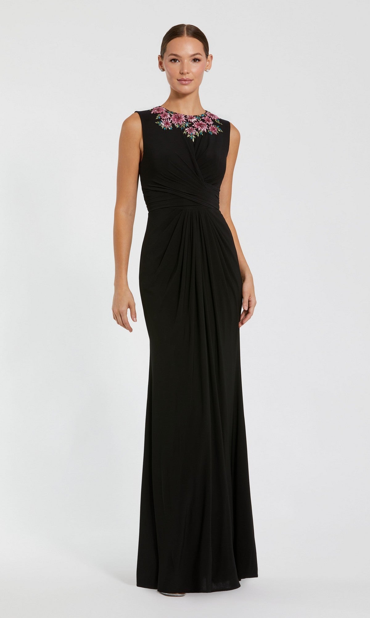 A woman stands against a plain light background wearing the Mac Duggal 11815 long formal dress in black multi, featuring a sleeveless design, floor-length cut, gathered waist, and rhinestone flower details at the neckline.