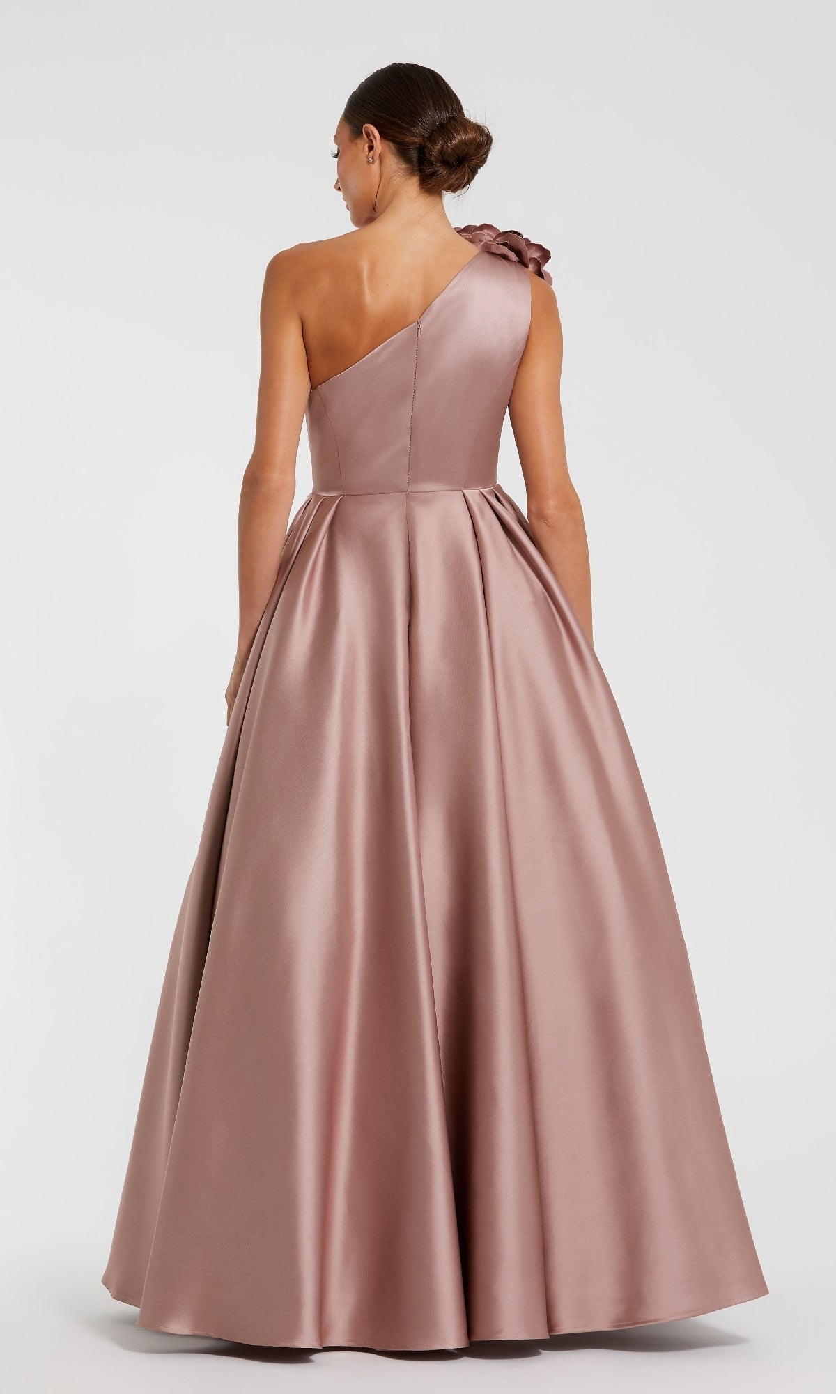 Woman wearing a one-shoulder pink ball gown on a white background